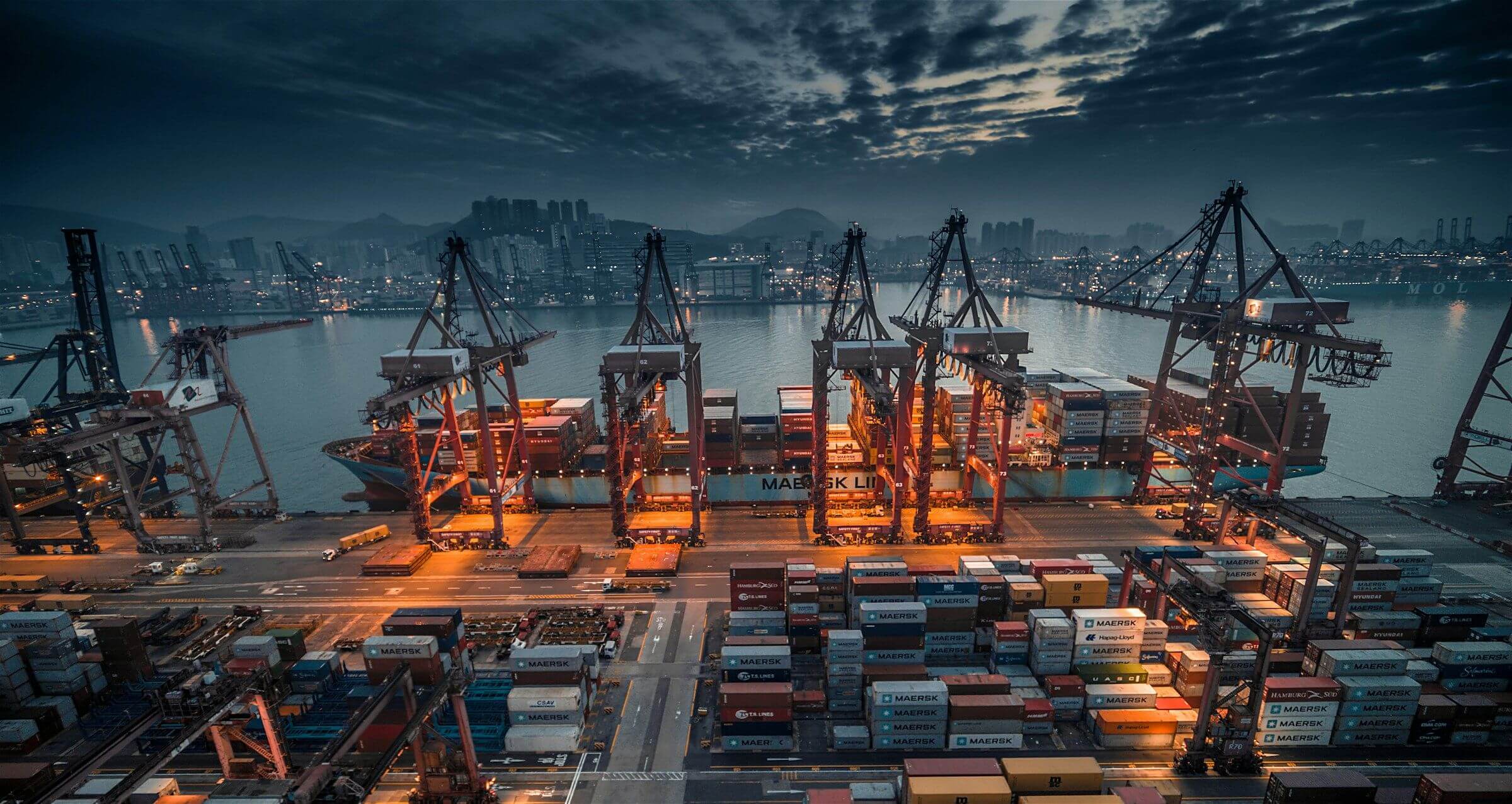 Container port with gantry cranes lit up at dusk