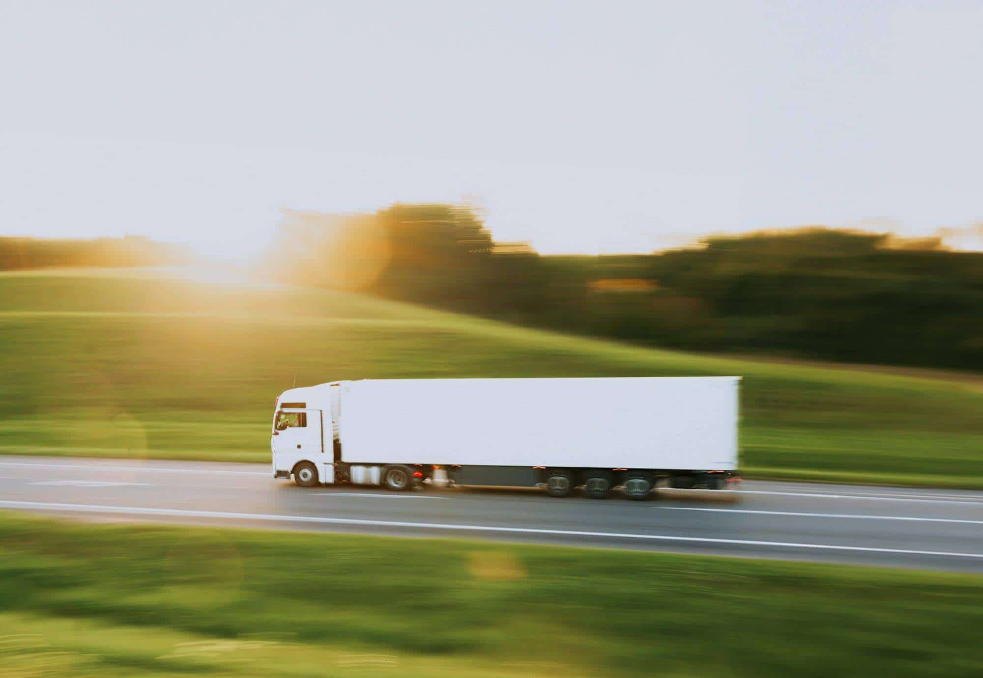 Truck speeding along a highway at sunset